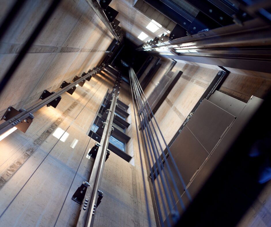 Vue en contre-plongée d'un puits d'ascenseur moderne mettant en évidence le mécanisme de verrou antidérive pour la sécurité.