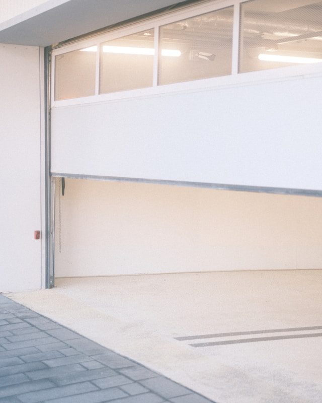 Porte de garage de parking souterrain en cours d’ouverture, illustrant la sécurisation par verrou électromagnétique