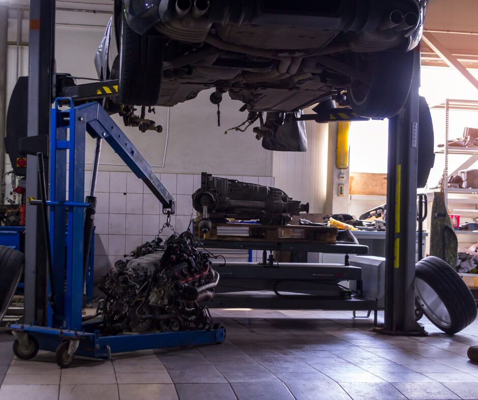 Table élévatrice hydraulique pour véhicule, avec système de levage sécurisé dans un atelier de réparation auto.